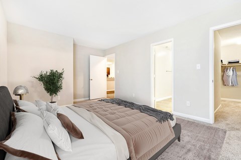 A bedroom with a large bed and a small tree on the nightstand.