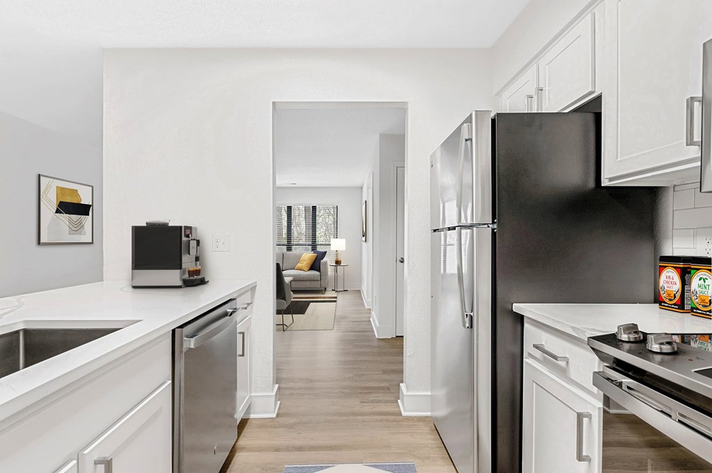 A modern kitchen with a black refrigerator and white cabinets. at Woodlyn on the Green Apartment Homes, Cary, North Carolina