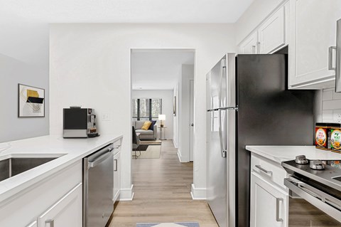 A modern kitchen with a black refrigerator and white cabinets.