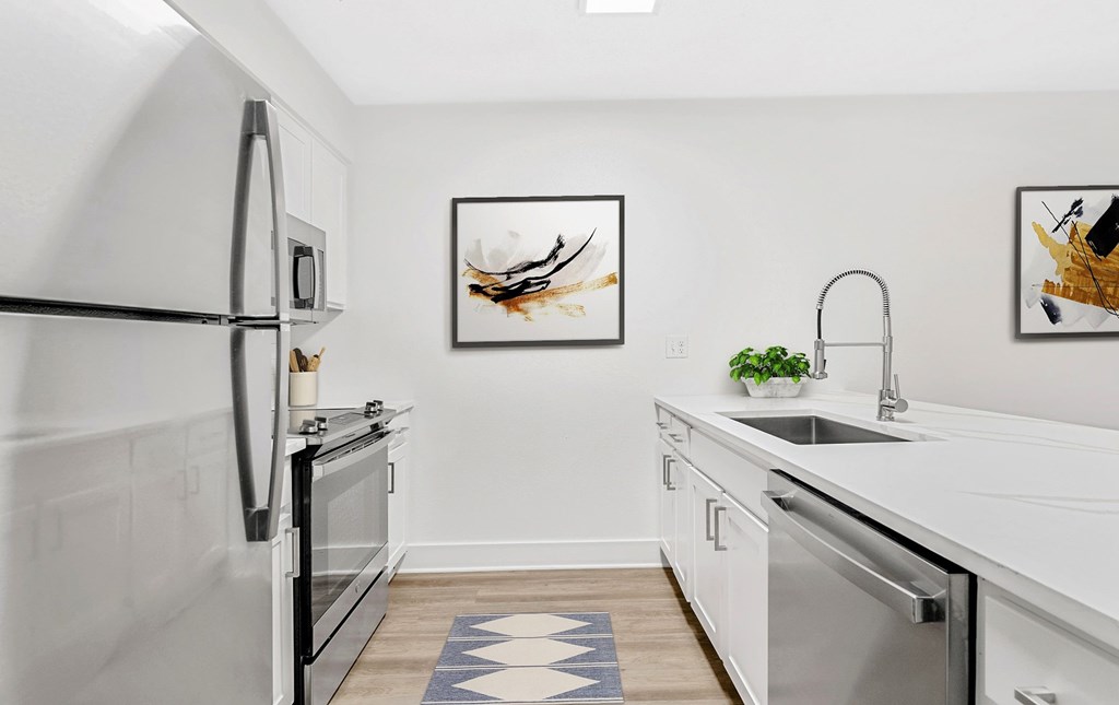 A modern kitchen with a white fridge, a sink, and a dishwasher. at Woodlyn on the Green Apartment Homes, Cary, NC