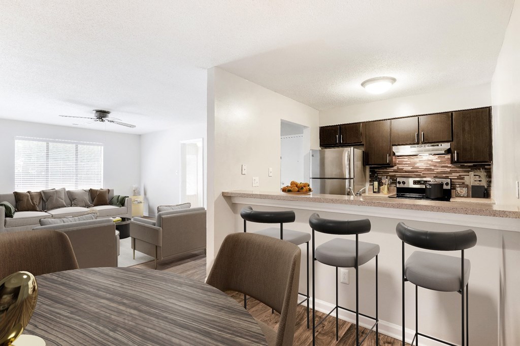 A modern kitchen with a bar stool and a dining table. at Woodlyn on the Green Apartment Homes, Cary, North Carolina