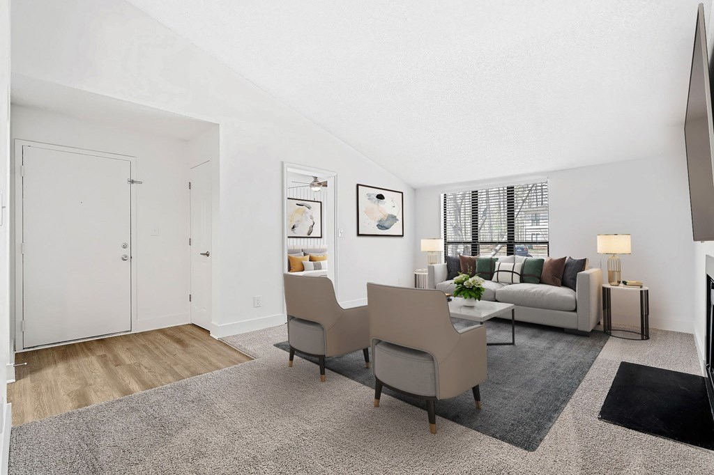 A living room with a grey carpet and a white sofa. at Woodlyn on the Green Apartment Homes, Cary, NC, 27513