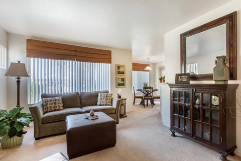 Carpeted Model Living Room with Couch, Ottoman and Buffett Cabinet Under Mirror