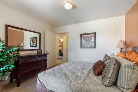 Model Bedroom with Bed and Dresser with Mirror Mounted Above it Next to Plant