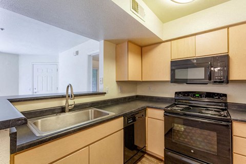 A kitchen with a black stove top oven and a black microwave above it.