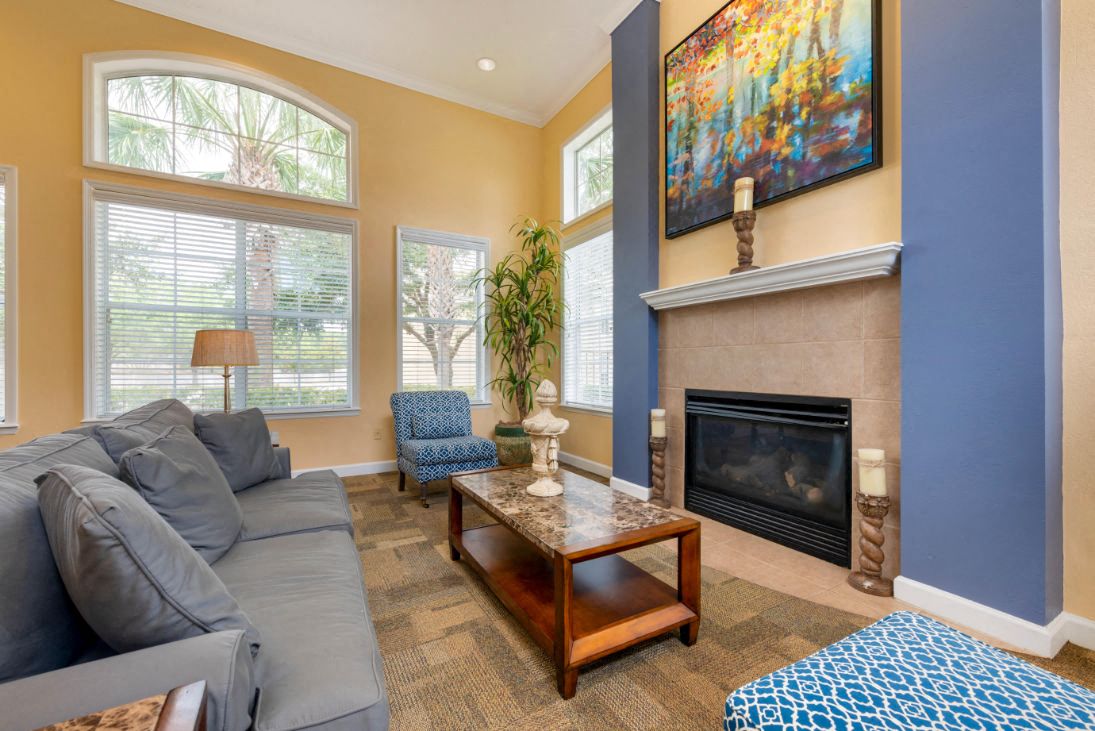 A living room with a grey couch, a coffee table, a fireplace, and a painting on the wall.