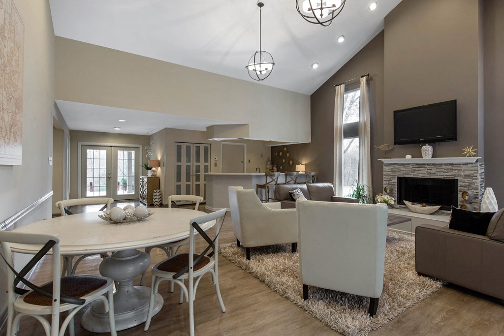 Leasing office interior waiting area with two couches, two chairs, dining table with chairs fireplace tv and kitchen area