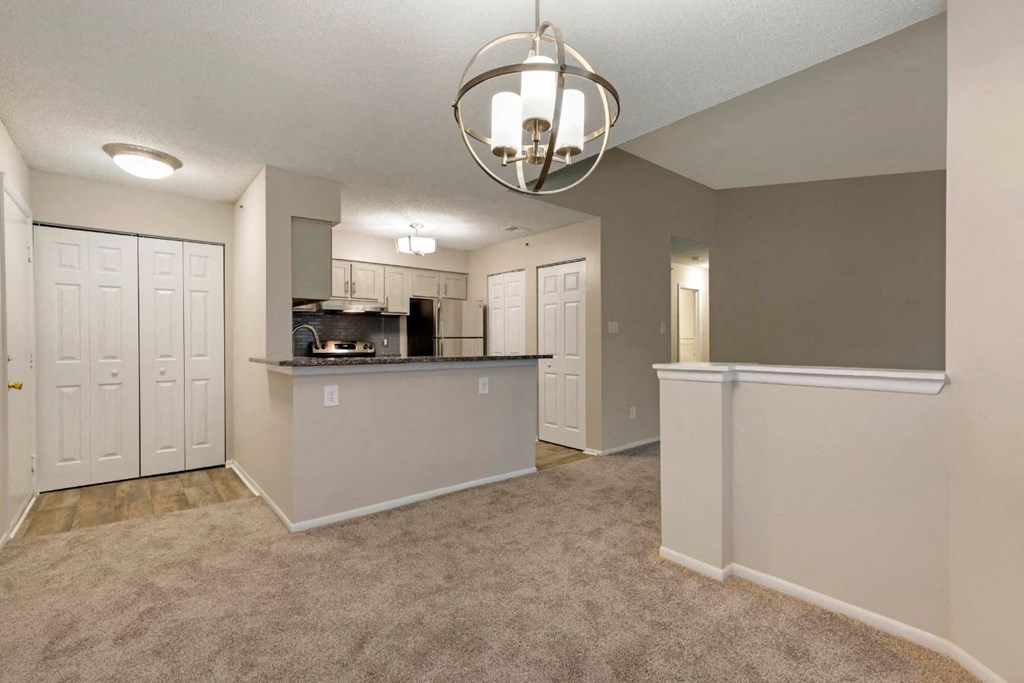 Carpeted Living Room Next to Kitchen with Breakfast Bar White Cabinets and Stainless Steel Appliances