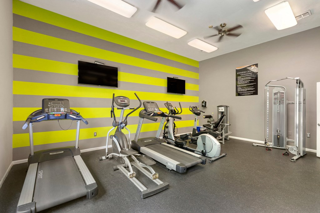 Fitness center with treadmills, ceiling fans and TVs.