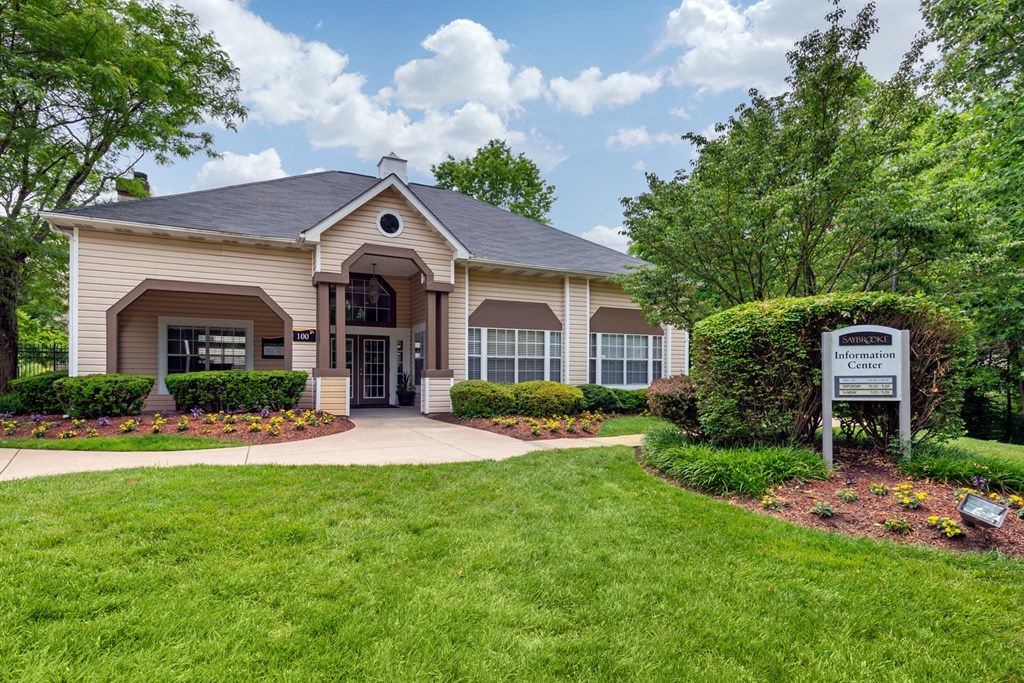 Leasing office exterior with large flower beds, bushes and the sidewalk