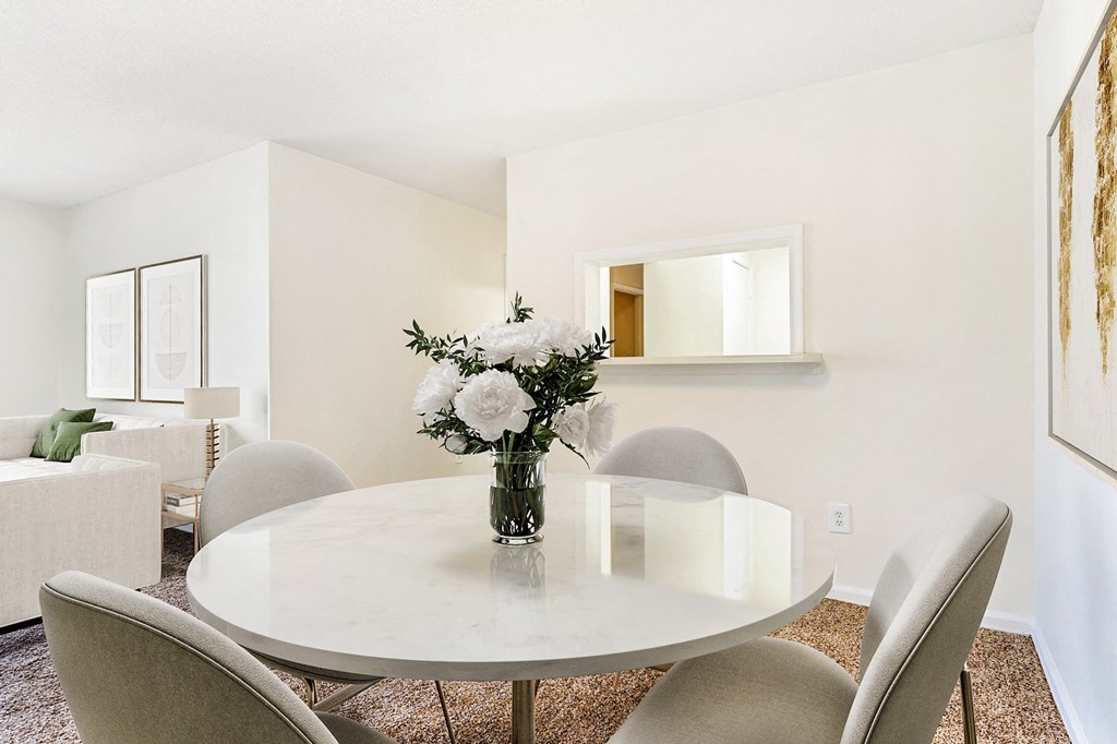 Carpeted living room and dining area with marble table and chair set with art above the wall and view of couches in the back.