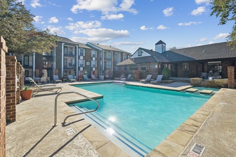 A swimming pool surrounded by a brick wall and a building in the background.