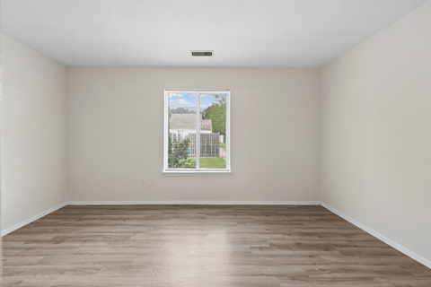 Empty room with a window showing a view of a building and trees.