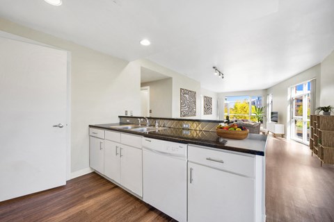 A kitchen with white cabinets and a wooden floor.