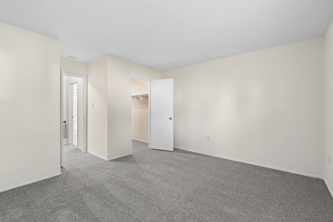 A large empty room with carpeted floor and white walls.