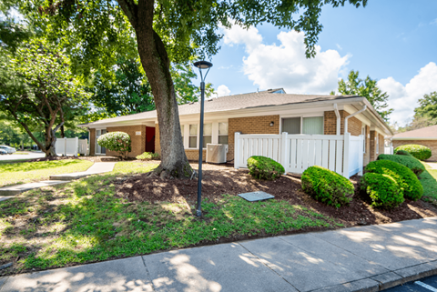 A house with a white picket fence and a tree in front.