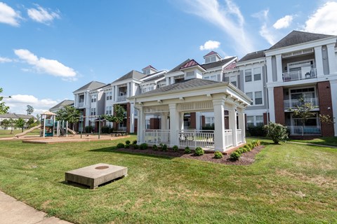 A large grassy area in front of apartment buildings with a concrete block in the foreground.