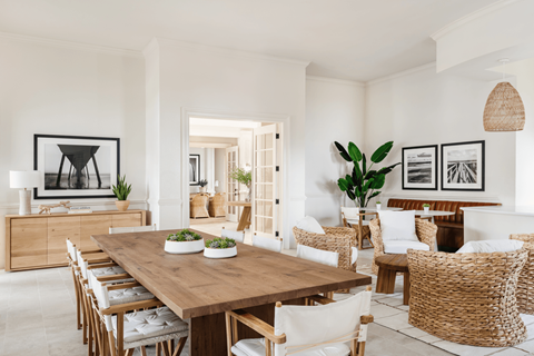 a white dining room with a wooden table and rattan chairs