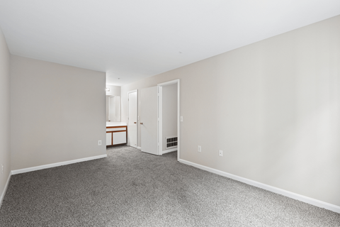 A room with a carpeted floor and a doorway leading to another room.