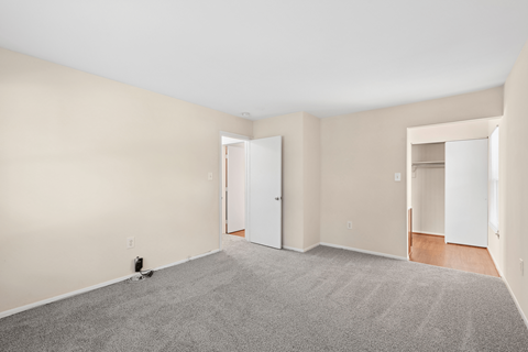 A room with a carpeted floor and two open doors.