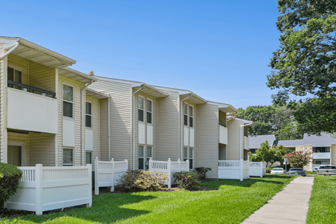 A row of white apartment buildings with green lawns in front.