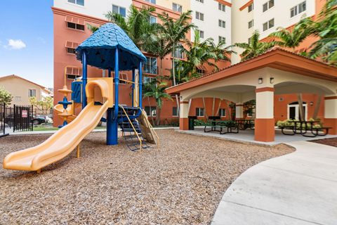 A playground with a yellow slide and a blue roofed structure.