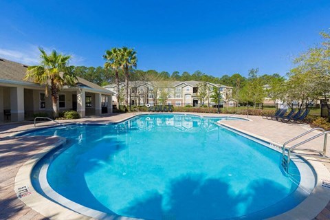 A swimming pool surrounded by palm trees and residential buildings.