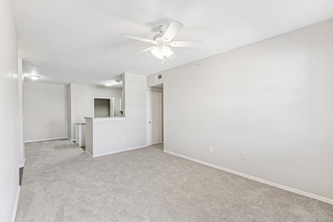 A spacious room with a ceiling fan and carpeted floor.