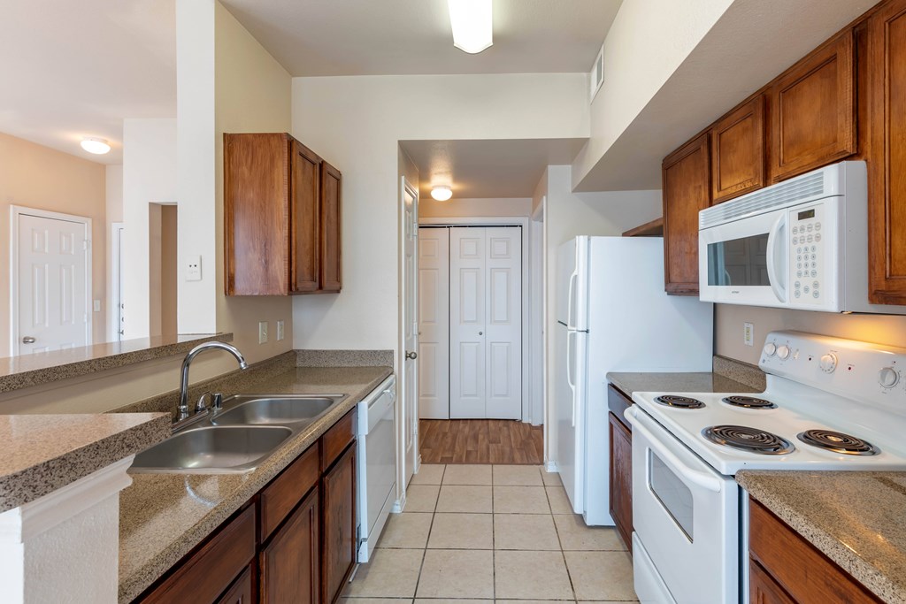 A kitchen with white appliances and brown cabinets.