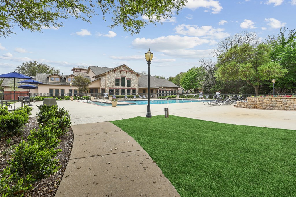 A sunny day at the park with a swimming pool and a building in the background.