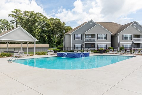 A swimming pool in front of a building with a covered patio area.