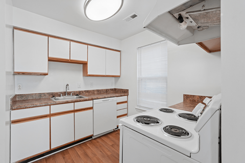 A kitchen with white cabinets and a white stove top oven.