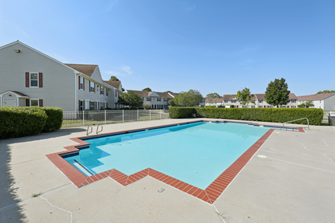 A swimming pool surrounded by a brick border in a residential area.