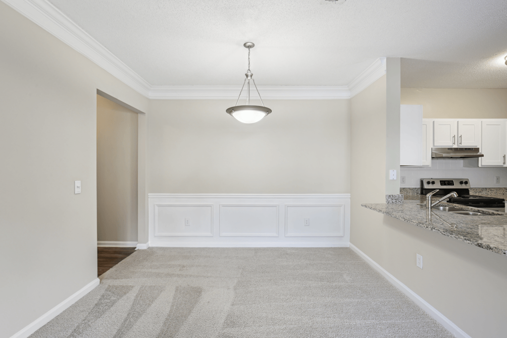 dining room with carpeted flooring and overhead lighting, with breakfast bar to the right