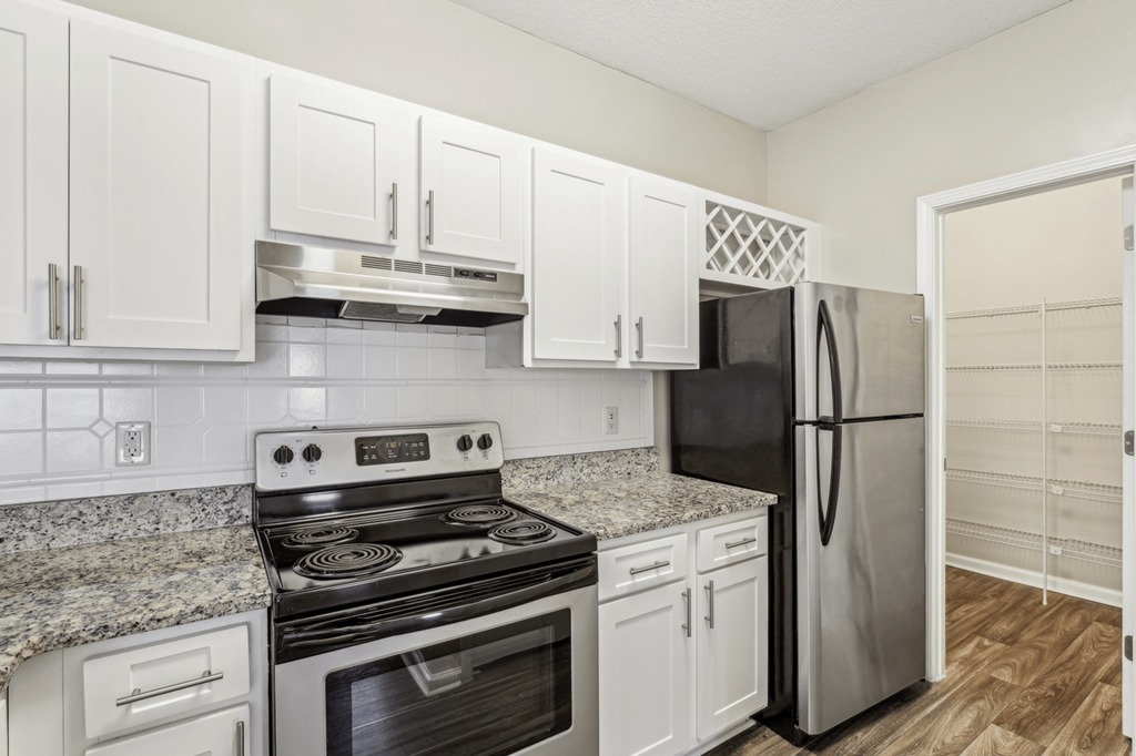 kitchen with white cabinetry, stainless steel appliances, and granite-style countertops
