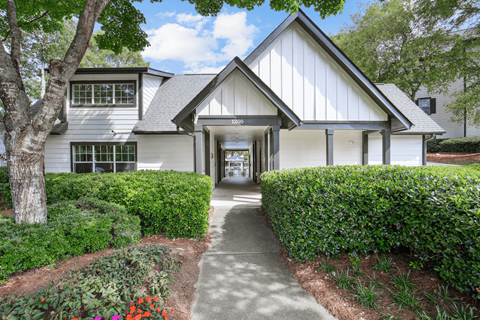 the front of a white house with a walkway and trees