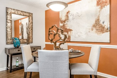 a dining room with orange walls and a table with white chairs