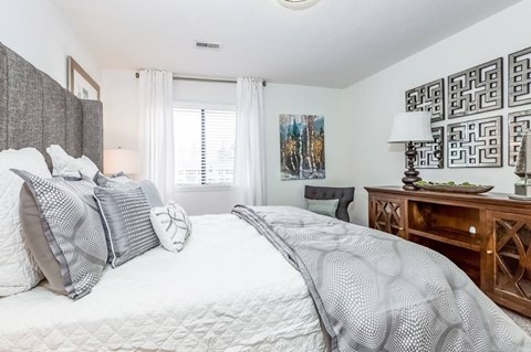 A bedroom with a large bed and a wooden dresser.