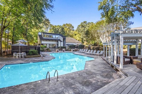 A large outdoor swimming pool surrounded by trees and a pavilion.
