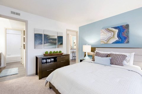 A bedroom with a large bed and a dresser with a mirror.