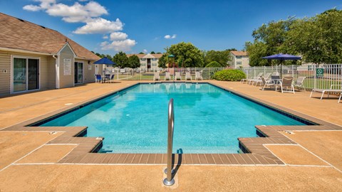 Swimming Pool and Sun Deck with Lounge Chairs with Trees and Building Exteriors in the Background