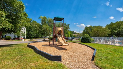 Playground on Mulch in Grassy Courtyard Next to Fenced in Swimming Pool