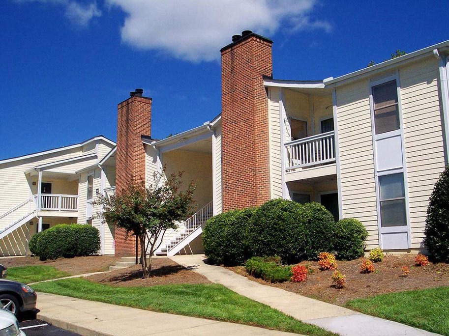A white house with a red brick chimney at Fox Hollow Apartment Homes, High Point, 27265
