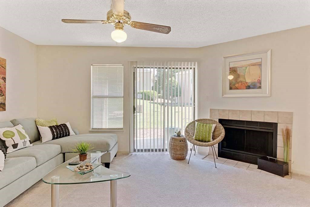 A living room with a fireplace, a couch, a chair, and a table at Fox Hollow Apartment Homes, High Point