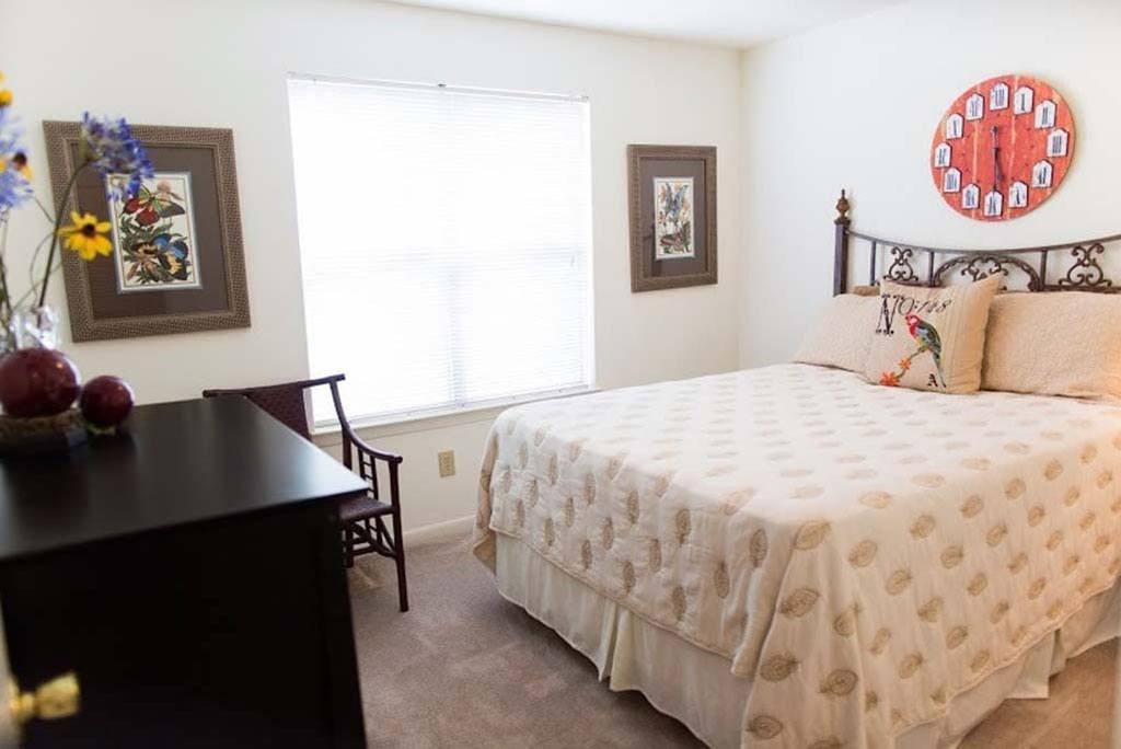 A bedroom with a bed, a chair, and a dresser at Fox Hollow Apartment Homes, North Carolina, 27265