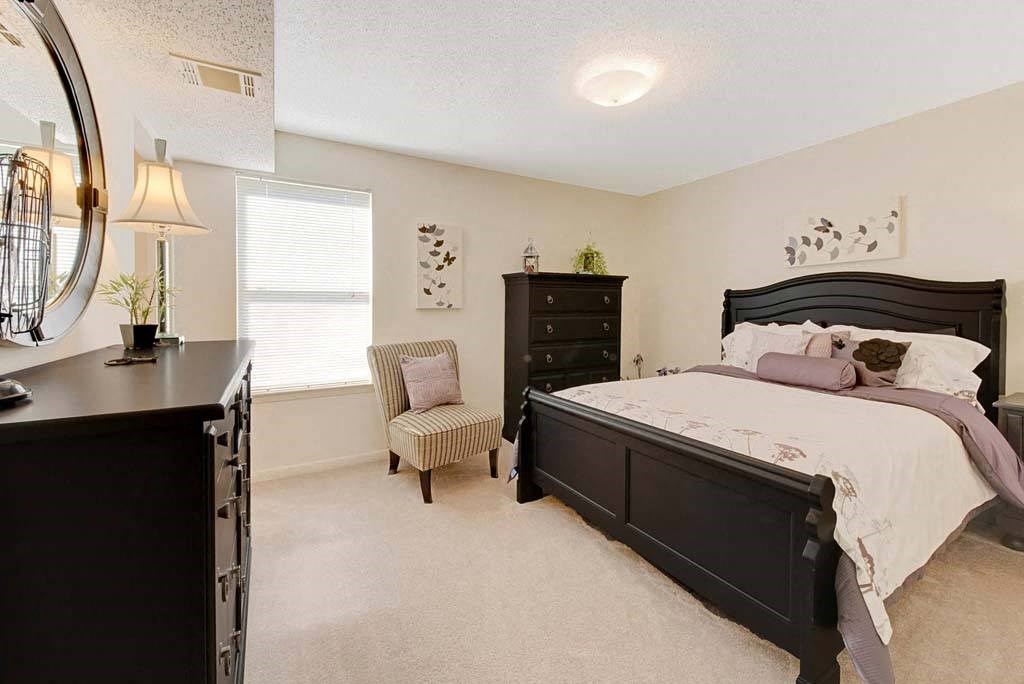 A bedroom with a large bed and a chair by the window at Fox Hollow Apartment Homes, North Carolina, 27265