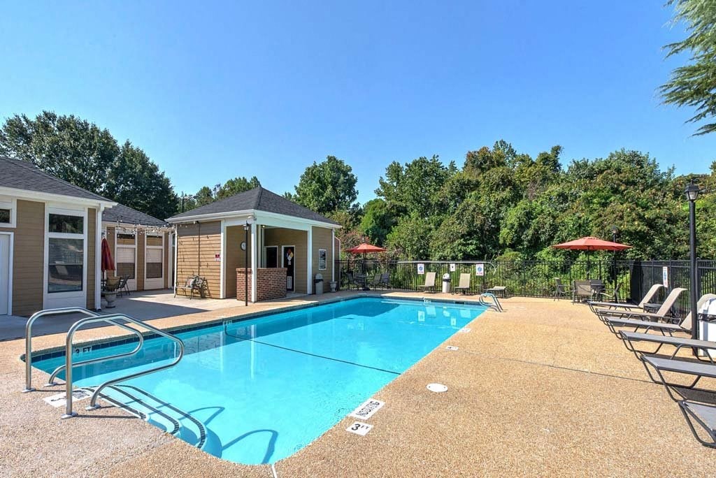 A swimming pool surrounded by trees and chairs at Fox Hollow Apartment Homes, High Point, North Carolina
