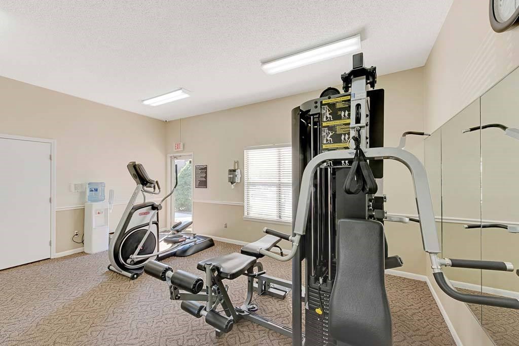 A gym with a treadmill, elliptical trainer and a weight machine at Fox Hollow Apartment Homes, High Point, 27265