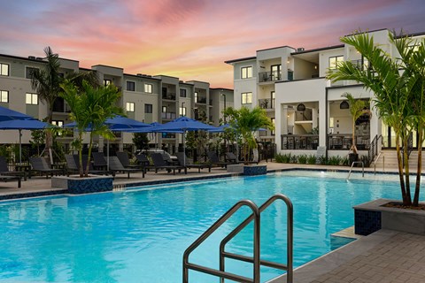 a swimming pool at sunset at an apartment complex