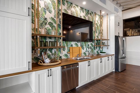 A kitchen with a white cabinet and a green leafy wallpaper.
